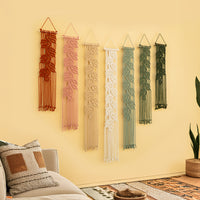 Set of six macrame wall hangings in various colors on a yellow wall.
