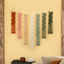 Set of six string art pieces in various colors hanging on a yellow wall.