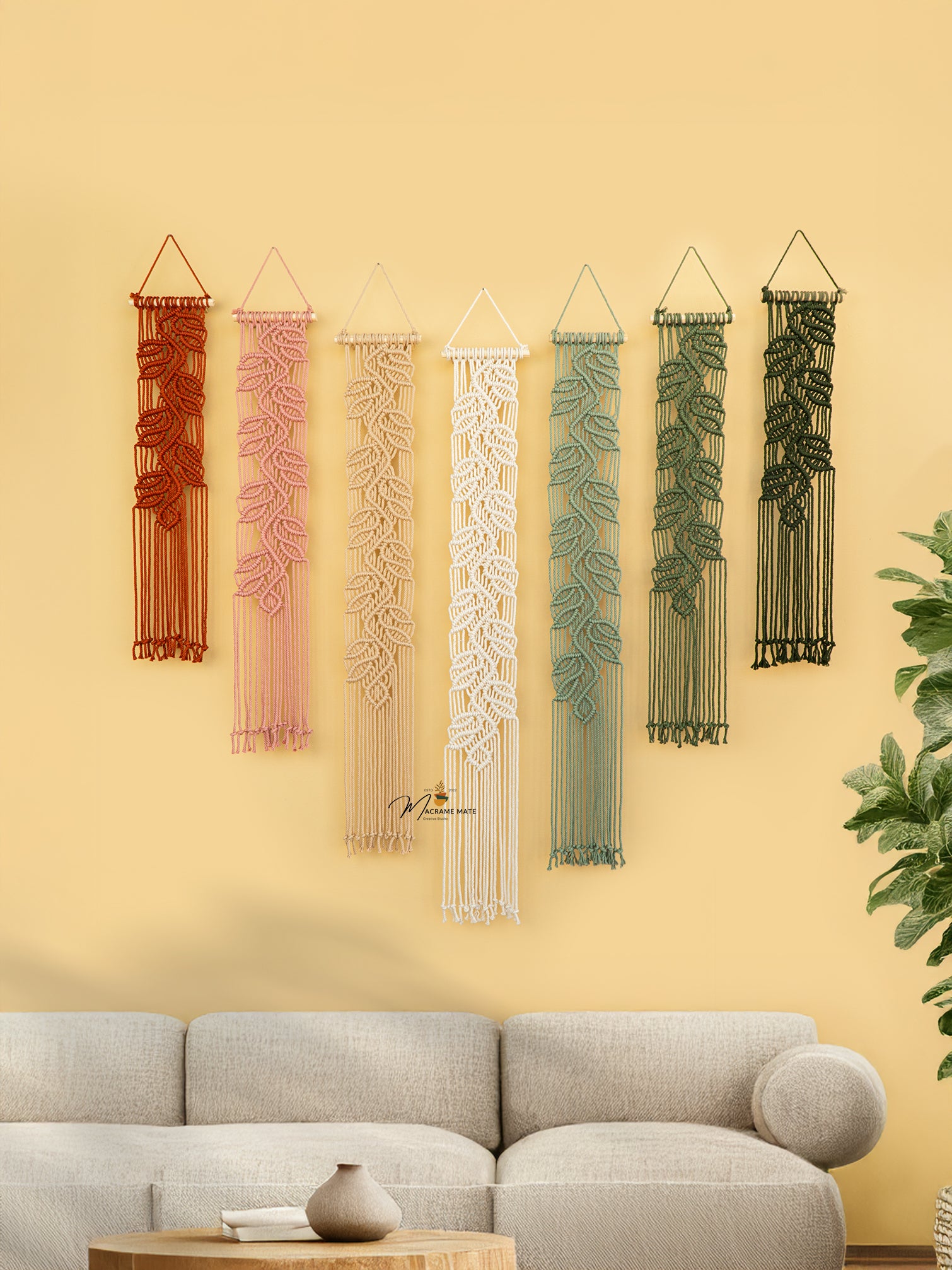 Set of six decorative wall hangings with different patterns on a yellow wall above a gray sofa.