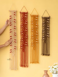 Set of four macrame wall hangings in different colors on a yellow wall.