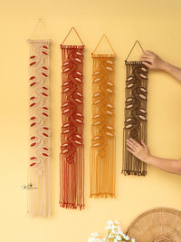 Four macrame wall hangings of different colors on a yellow background