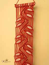 Macrame wall hanging with red and white pattern on a beige background