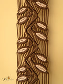 Close-up of a macrame belt with leaf patterns on a beige background