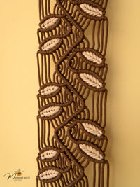Close-up of a macrame belt with leaf patterns on a beige background