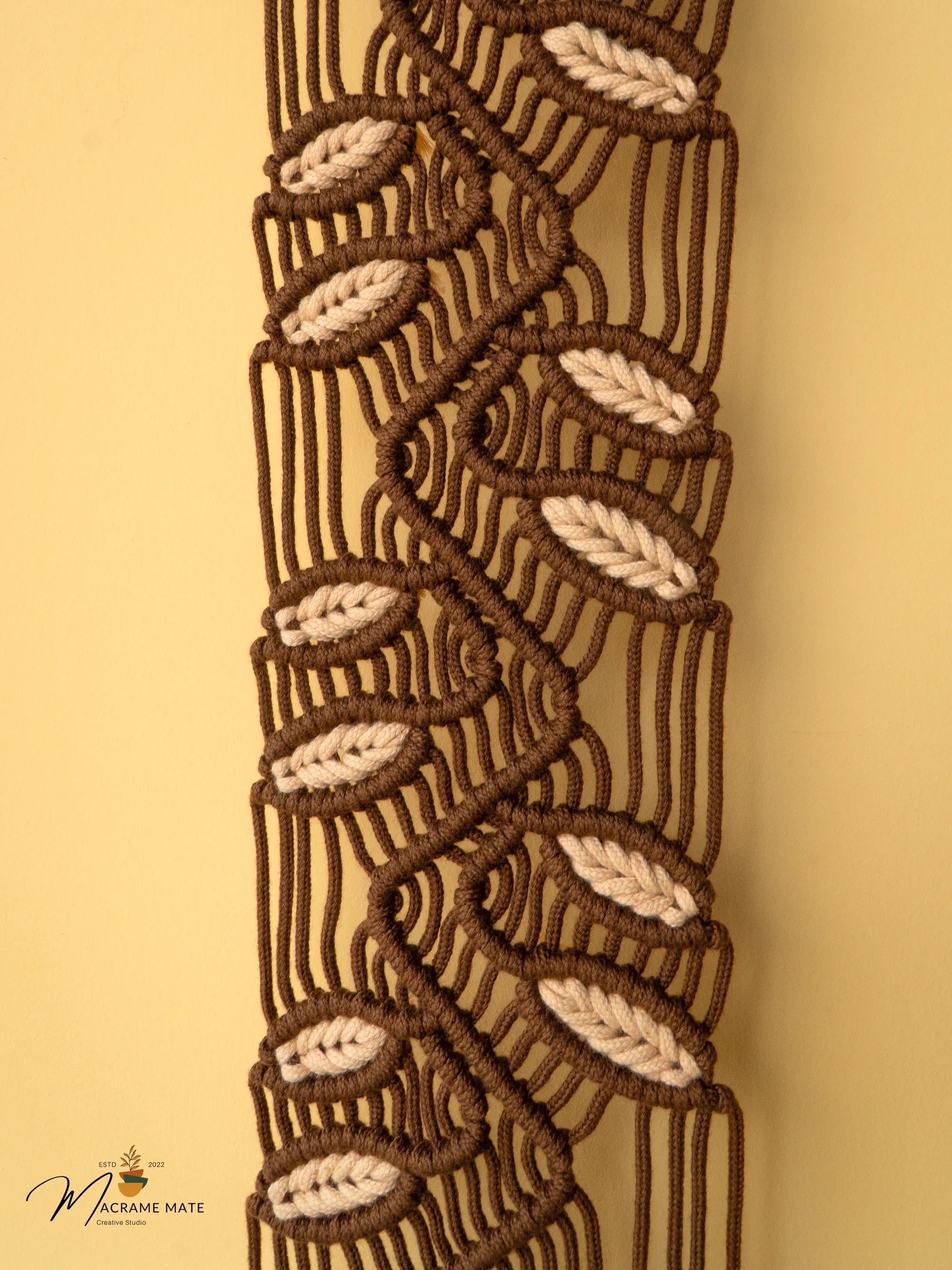 Close-up of a macrame belt with leaf patterns on a beige background