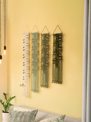 Four decorative wall hangings with leaf patterns on a yellow wall.