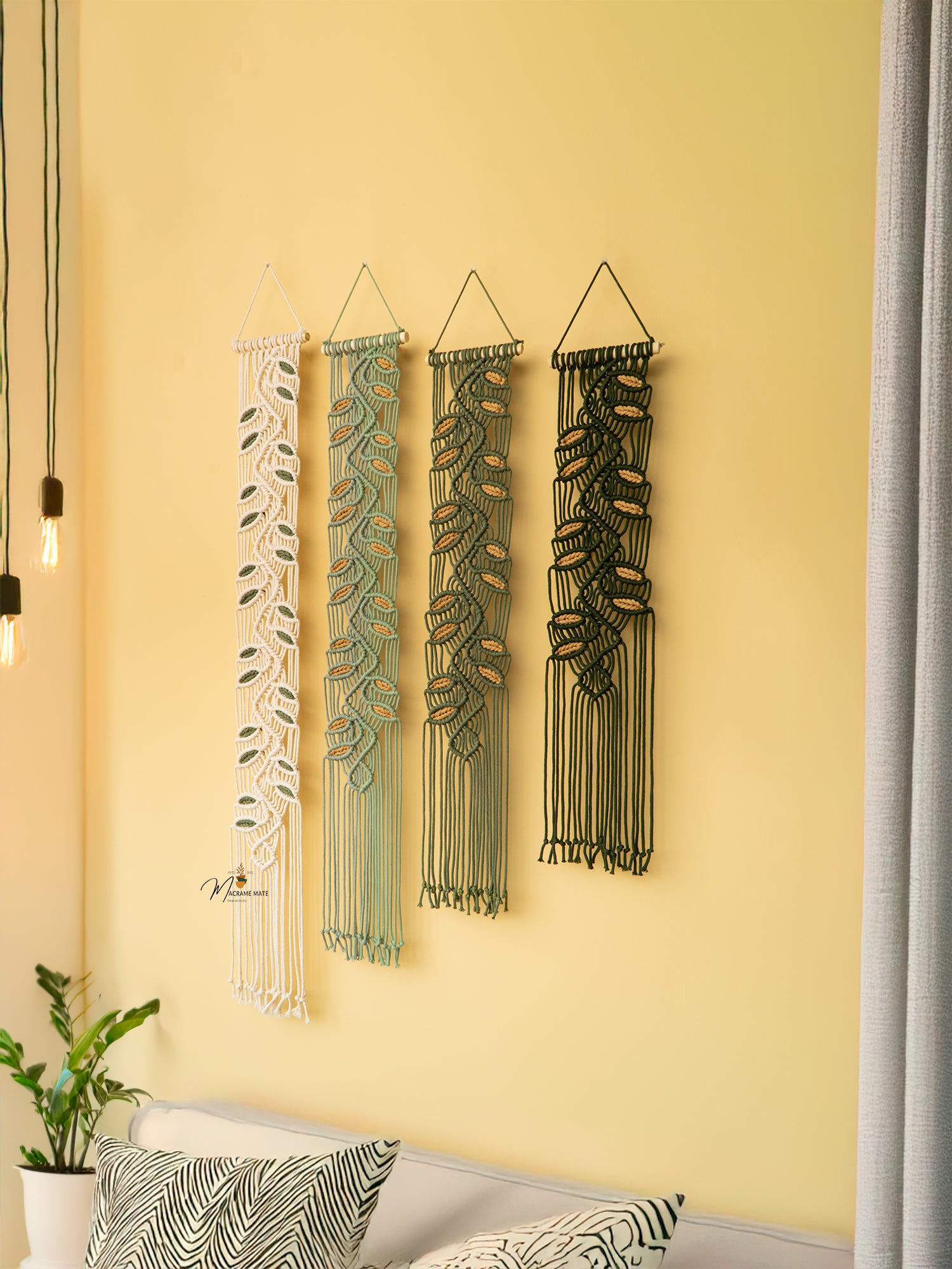 Four decorative wall hangings with leaf patterns on a yellow wall.
