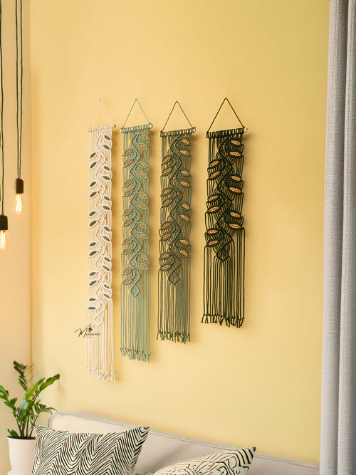 Four decorative wall hangings with leaf patterns on a yellow wall.