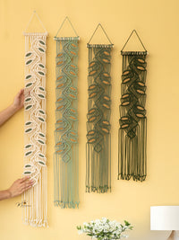 Four macrame wall hangings of different designs on a yellow wall.