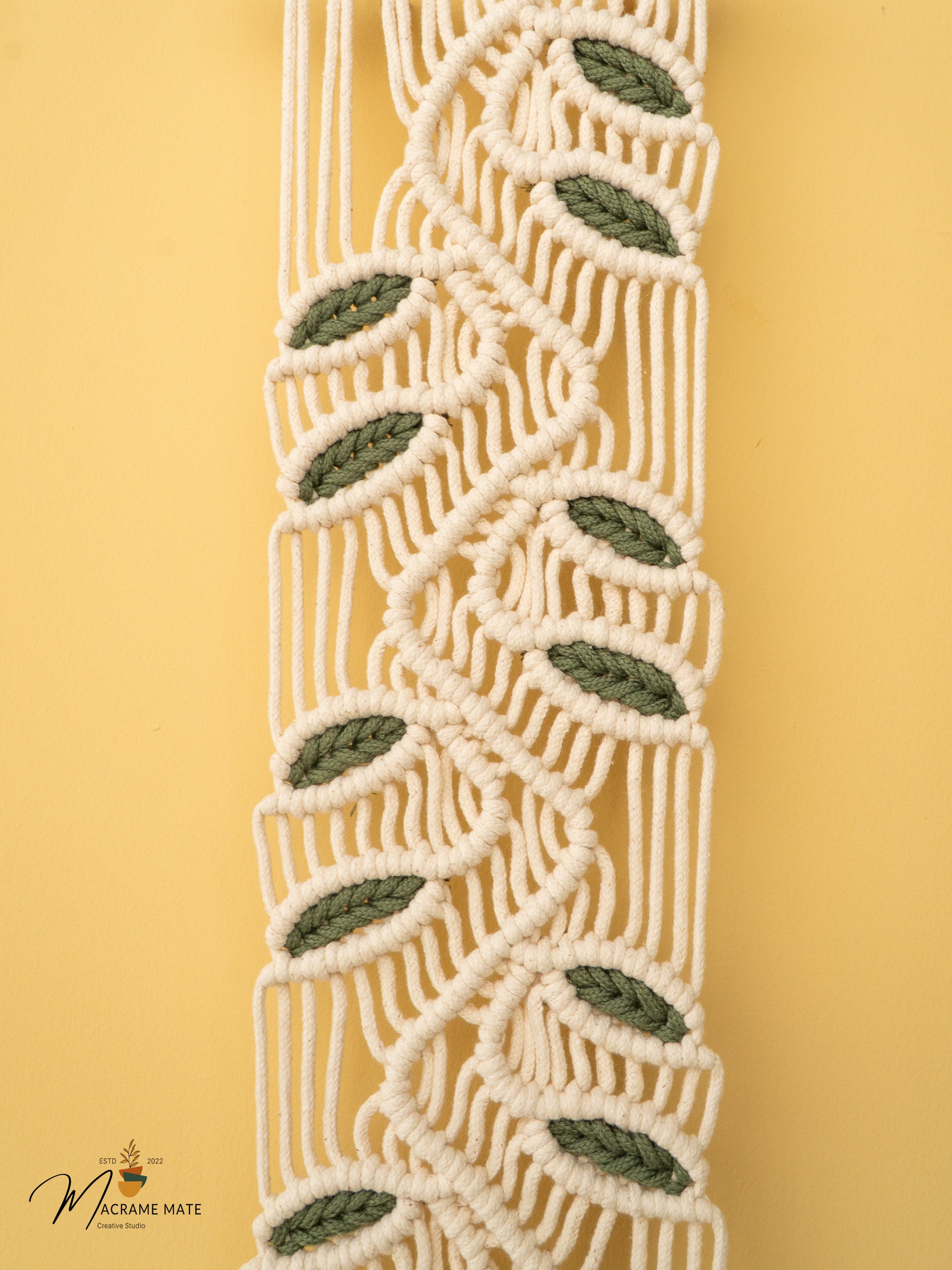 Macrame plant hanger with leaf patterns on a yellow background